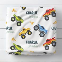 a blanket with monster trucks on it and name written across the front in bright colors