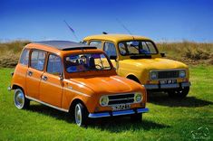 two old cars are parked in the grass