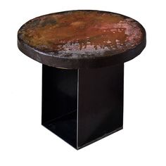 a round metal table with rusted paint on it's surface and black base