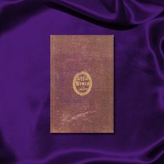 an old book with the title little women written on it in gold and purple colors