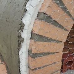 the cement is being poured onto the side of a building with chicken wire around it