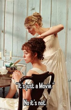 two women in white dresses sitting next to each other and one is touching her hair