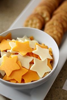 a white bowl filled with cheese and star shaped cookies next to crackers on a table