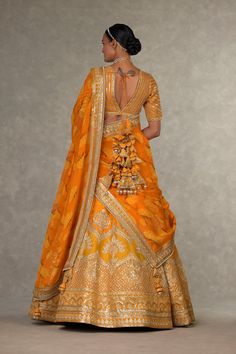 Dress in sophistication with this digital-printed patchwork lehenga, featuring chaand-phool and jhaali motifs in gold dori, sitara, and moti kaam. The lehenga is adorned with an embroidered border and kinari edging, along with a side zip closure and pocket detailing. The can can skirt blouse boasts sitara kaam, a 'V' neckline, elbow sleeves, and a center back opening with a tie-up tassel detail. The ensemble is completed with an all-over digital printed organza dupatta, embellished with an embro Red Gharchola Saree, Rust Lehenga, Patchwork Lehenga, Can Can Skirt, Cancan Skirt, Embellished Embroidery, Lehenga And Blouse, Orange Lehenga, Caribbean Fashion