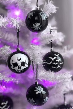 three black and white ornaments hanging from a christmas tree with purple lights in the background