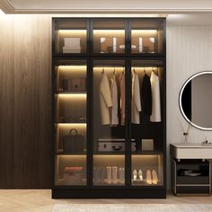 a walk in closet with clothes and shoes on shelves next to a mirror that is lit up