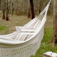 a white hammock hanging from a tree in the woods