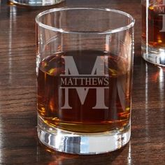 two glasses with the letter m on them sitting on a table