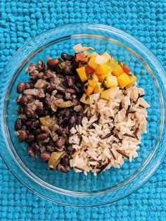 a glass bowl filled with rice, beans and other vegetables on top of a blue towel