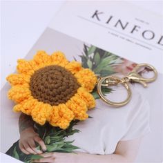 a crocheted sunflower keychain sitting on top of a magazine