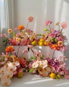 an arrangement of flowers and fruit on a table