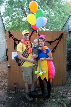 a man and woman in costumes holding a baby with balloons attached to the back of their heads