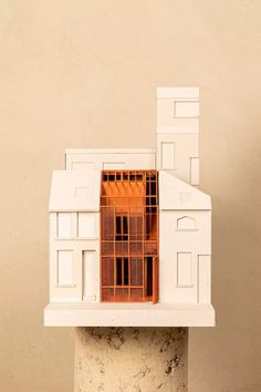 a model of a house on top of a white pedestal with an orange roof and windows