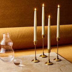 four candles on a table next to a vase