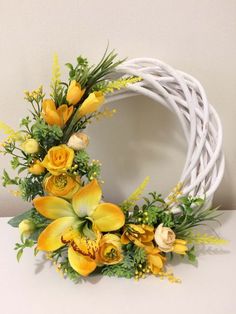 a white wicker wreath with yellow flowers and greenery