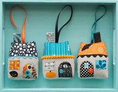 three small houses are hanging on a blue shelf with black and white polka dot ribbon