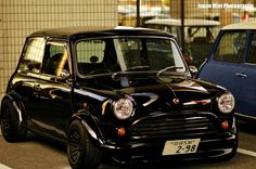 a small black car parked next to another blue car