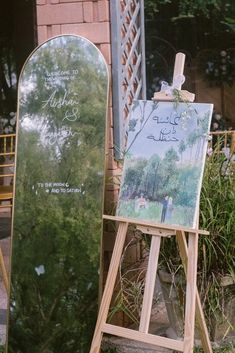 an easel with a painting on it next to a sign in front of a building