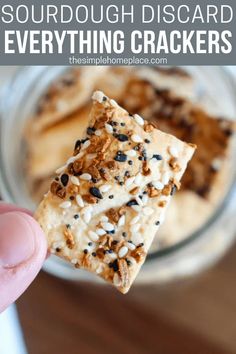 a hand holding up a cracker with black and white sprinkles