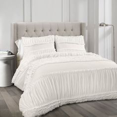 a white bed with ruffled bedspread and pillows