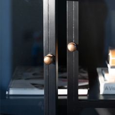 a black cabinet with two brass knobs on the front and back doors, sitting next to a stack of books