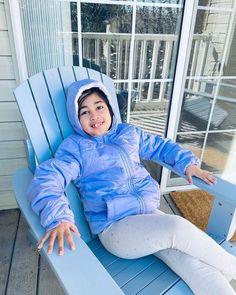 a young child sitting on a blue adiron chair