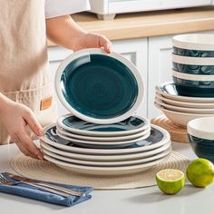 a person stacking plates on top of each other with limes in the background