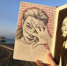 a person holding up a drawing in front of a beach with two people on it