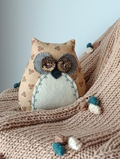 an owl stuffed animal sitting on top of a blanket