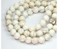 two strands of white marble beads on a white surface with one bead in the middle