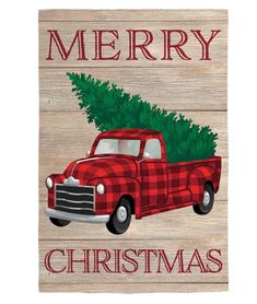 a red truck with a christmas tree on the back is sitting in front of a wooden sign