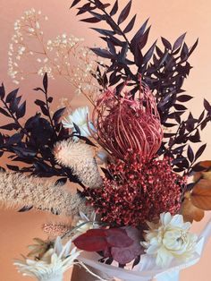 a vase filled with lots of different types of flowers and plants on top of a table