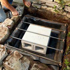 a man is working on an electrical box in the middle of some rocks and dirt