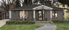 a small gray house sitting on top of a lush green field next to a sidewalk