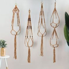 several macrame hangings on a wall next to a potted plant