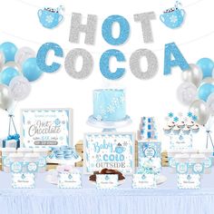 a table topped with cake and desserts covered in blue frosted icing next to a sign that says hot cocoa