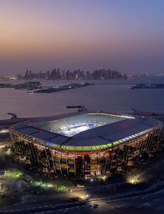 an aerial view of a large stadium with the city skyline in the background at night