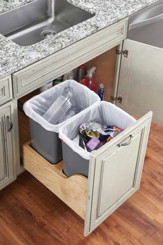 two bins are open in the middle of a kitchen counter with sink and cabinets