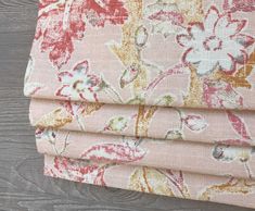 four pink and yellow floral fabric on top of each other, with wood flooring in the background