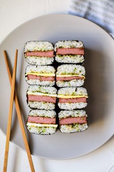 there are many sushi rolls on the plate with chopsticks next to it