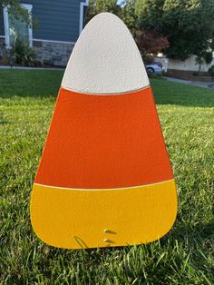 an orange, white and yellow cone shaped object in the grass