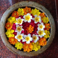 a bowl filled with flowers on top of a red and yellow flooring next to a wall