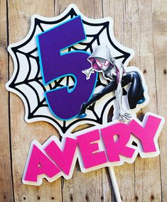 the number five sticker is next to a spiderman cake topper on a wooden table