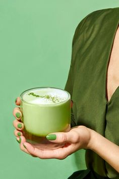 a woman holding a green drink in her hand