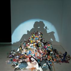 a pile of trash sitting on top of a floor next to a shadow of a man