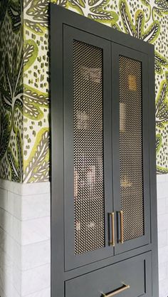 a black cabinet sitting in front of a wall with green and yellow designs on it