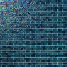 a close up view of a blue brick wall with different colored tiles on the side