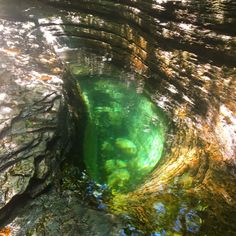 the water is very clear and green in this cave type hole, which looks like it has been dug into some rocks