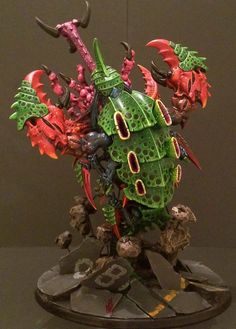 a green and red warhammer with horns on it's head sitting on a table