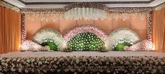 an elaborate table with flowers and greenery on the top is surrounded by orange drapes